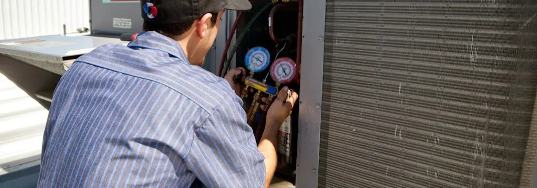 HVAC technician servicing a condenser unit in Willowbrook